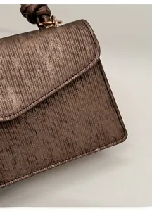 Detail of scratch-resistant brown striped fabric and golden hardware on the handbag