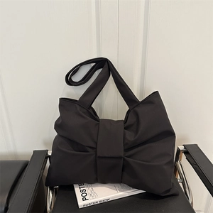 Minimalist black bow-knot shoulder bag in matte fabric on a designer chair