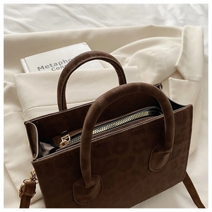 Dettaglio borsa marrone scuro con goffratura leopardata, doppi manici e zip dorata