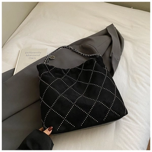 Detail of black suede bucket bag featuring silver quilted stitching and chain strap