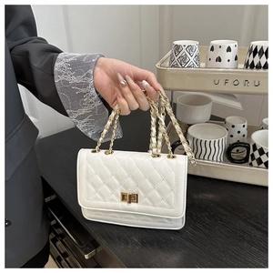 Detailed close-up of white quilted leather texture with elegant gold chain and square lock