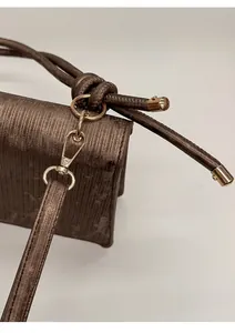 Close-up of detachable light gold hardware and ribbed texture on dark brown handbag
