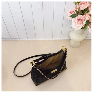 Close-up of leopard print texture fabric on black luxury shoulder bag with gold metal clasp