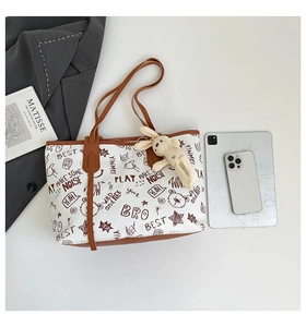 Detailansicht der weißen Totebag mit Graffiti-Prints und süßem Plüsch-Hasen-Anhänger