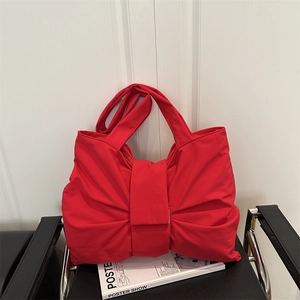 Red bow-shaped fabric handbag on a leather chair for a modern minimalist style
