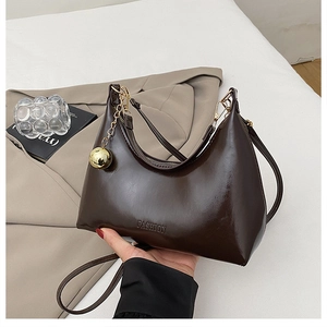 Détail du sac en cuir marron poli avec ornement sphérique doré et logo FASHION embossé