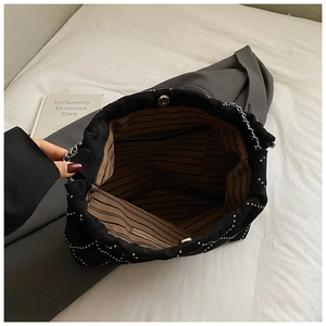 Top view of bucket bag showing striped lining, magnetic closure and silver chain strap