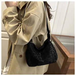 Detail of minimalist black leopard print crossbody bag featuring soft textured fabric