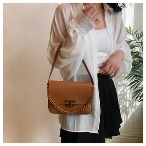Brown leather crossbody bag detail featuring a gold chain strap and metal T-logo buckle