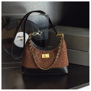 Detail of hobo bag featuring leopard print, black leather bottom, and gold metal clasp
