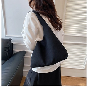Side view of large black minimalist tote bag worn by model in a modern interior setting