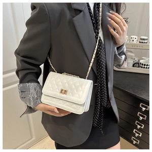 White quilted crossbody bag with gold chain strap worn over a dark blazer detail