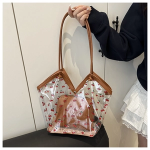 Dettaglio della borsa tote in PVC trasparente con ciliegie e finiture in pelle marrone
