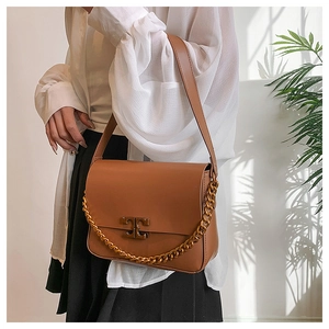 Detail of caramel leather shoulder bag with gold chain and metal logo buckle