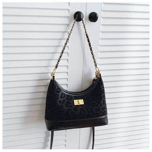 Close-up of leopard print shoulder bag with gold twist lock and chain strap on white door