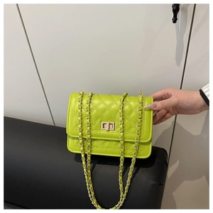 Detail of neon green quilted crossbody bag with gold chain strap and turn-lock closure