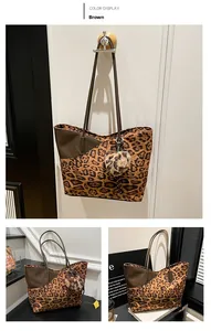 Close-up of leopard print tote bag with brown leather trim and soft pompom charm