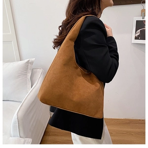 Brown faux suede oversized tote bag worn by a model in a minimalist interior setting