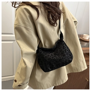 Close-up of leopard print velvet underarm bag with black shoulder strap worn by model