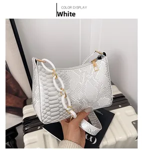Close-up of white snakeskin textured shoulder bag with thick acrylic chain and zipper
