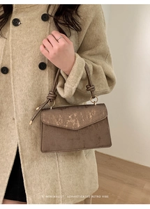 Detailed texture of brown retro flap bag with gold metallic ring and knot handle detail