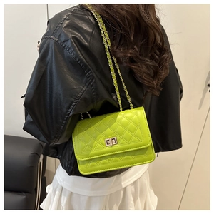 Detail of neon green quilted crossbody bag with silver clasp and leather chain strap