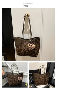 Detail view of large leopard print tote bag in brown with plush heart keychain charm