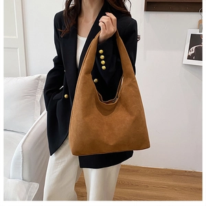 Detail of soft brown suede hobo bag with large capacity shown on a shoulder