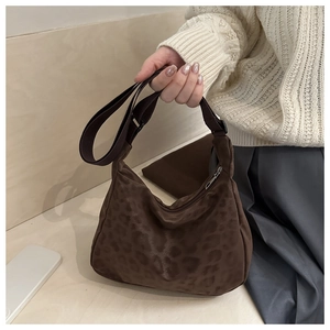Close-up of leopard print underarm bag with adjustable strap in soft autumn texture