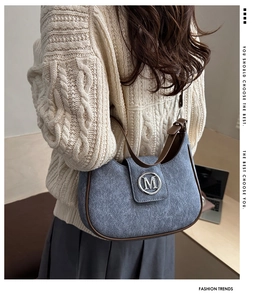 Detail of vintage gray textured underarm bag with leather trim and metallic M logo