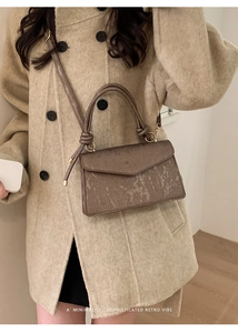 Close-up of a bronze retro textured crossbody bag with V-shaped flap and top handle