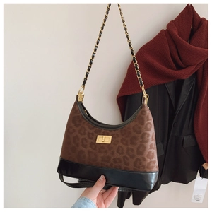 Detail of leopard print crossbody bag with chain strap and gold clasp on black blazer