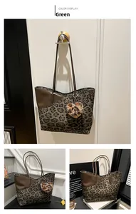 Detail of leopard print tote bag in green canvas with leather trim and plush heart charm