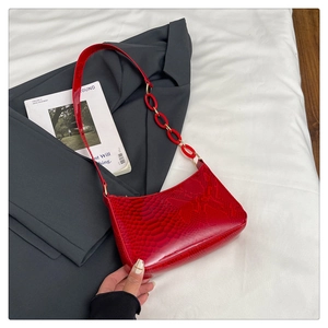 Close-up of red snakeskin embossed patent leather underarm bag with acrylic chain detail
