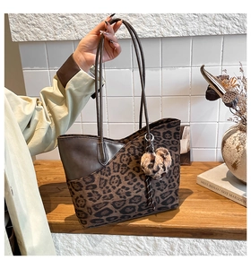 Detail of leopard print tote bag with brown leather accents and heart plush charm