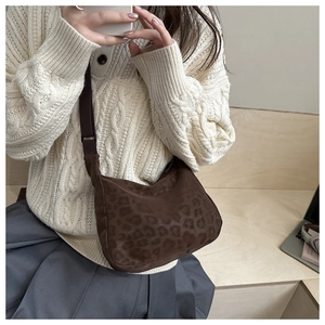 Close-up of leopard print crossbody bag with wide nylon strap on a model outfit