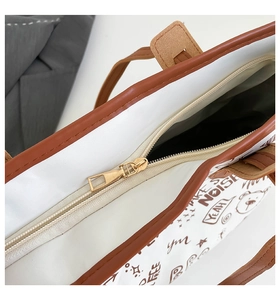 Detailaufnahme des goldenen Reißverschlusses und braunen Graffiti-Drucks auf der Tasche