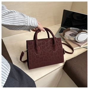 Dettaglio di una borsa rosso scuro con motivo leopardato su una scrivania moderna