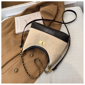 Detail of beige leopard print crossbody bag with golden twist lock on wool coat