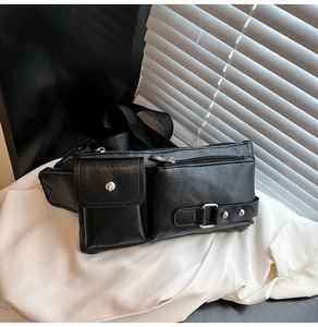 Detail of black pebbled leather crossbody bag with functional pockets and metal buckle