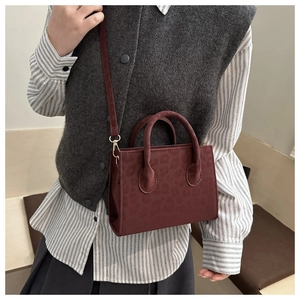 Detail of burgundy leopard print crossbody bag worn by a model in casual attire