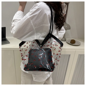 Detail of transparent PVC tote bag with red cherry print and black inner pouch on shoulder