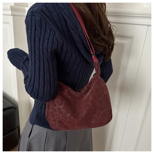 Detail view of burgundy leopard print tote bag with woven strap on woman's shoulder