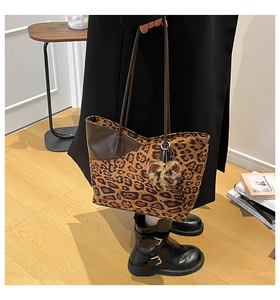 Detail of leopard print tote bag with brown leather patchwork and plush heart charm