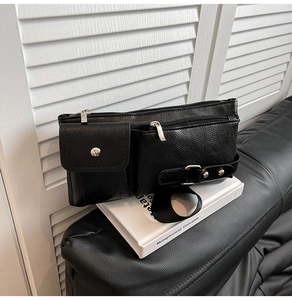 Detail of black pebbled leather crossbody bag with silver hardware and utility pockets
