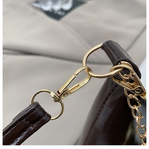 Vue détaillée du sac en cuir verni marron foncé avec chaîne et ferrures en métal doré