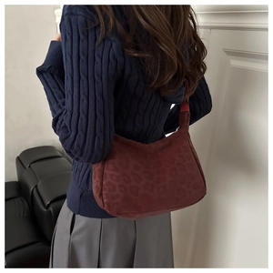 Detail of burgundy leopard print hobo bag worn over the shoulder on a knit sweater