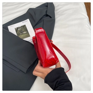 Detail view of red snakeskin embossed leather shoulder bag with glossy patent finish