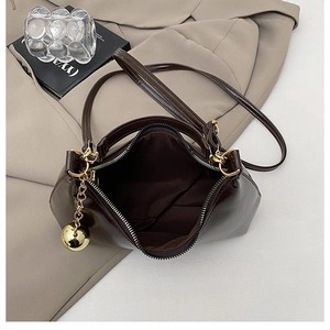 Détail du sac en cuir marron café avec fermeture éclair dorée et pendentif sphère
