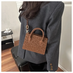 Leopard print mini handbag with brown textured finish worn as a crossbody bag